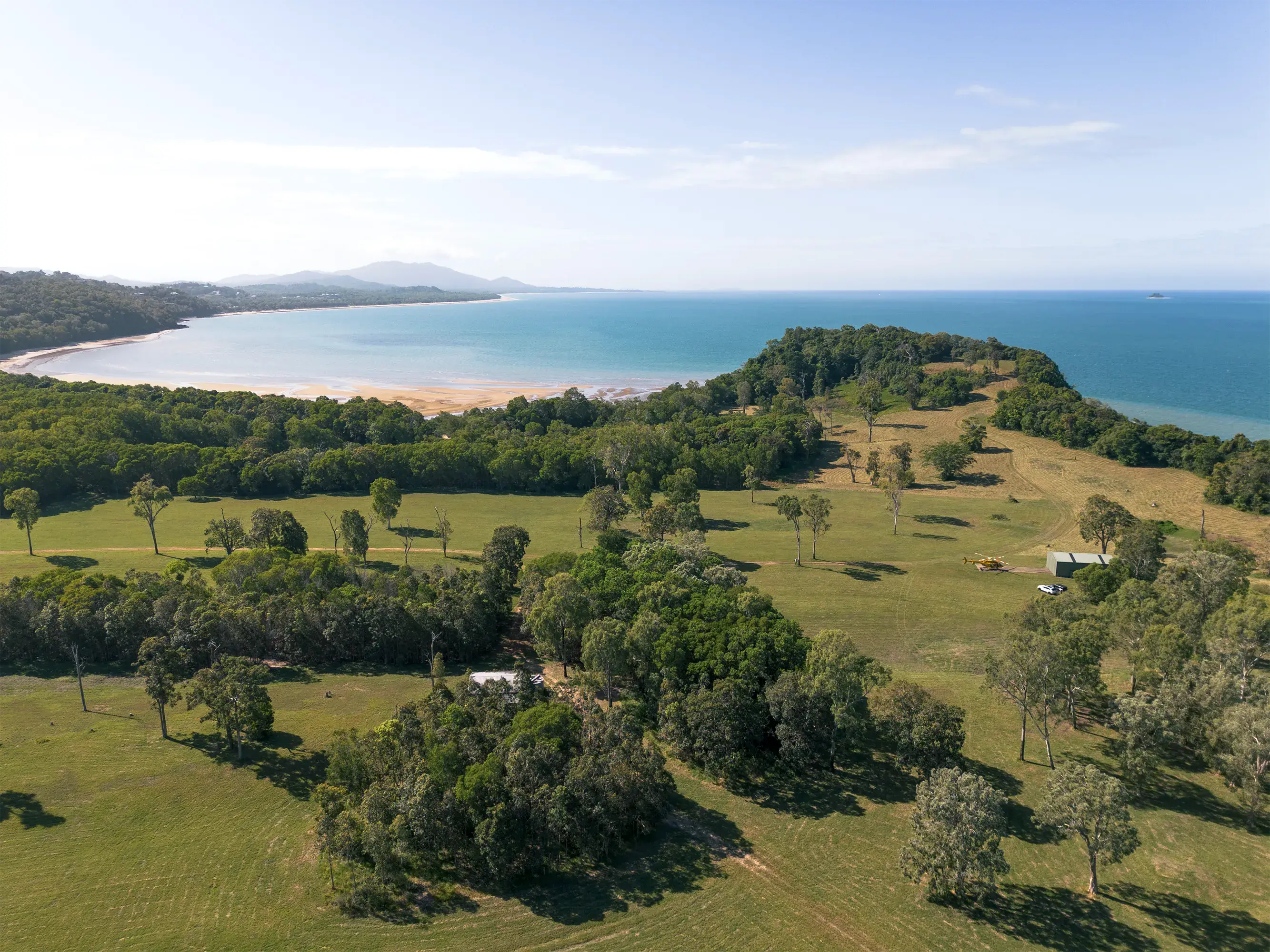 The cleared ground from above, rising towards the headland, the beach and bay beyond