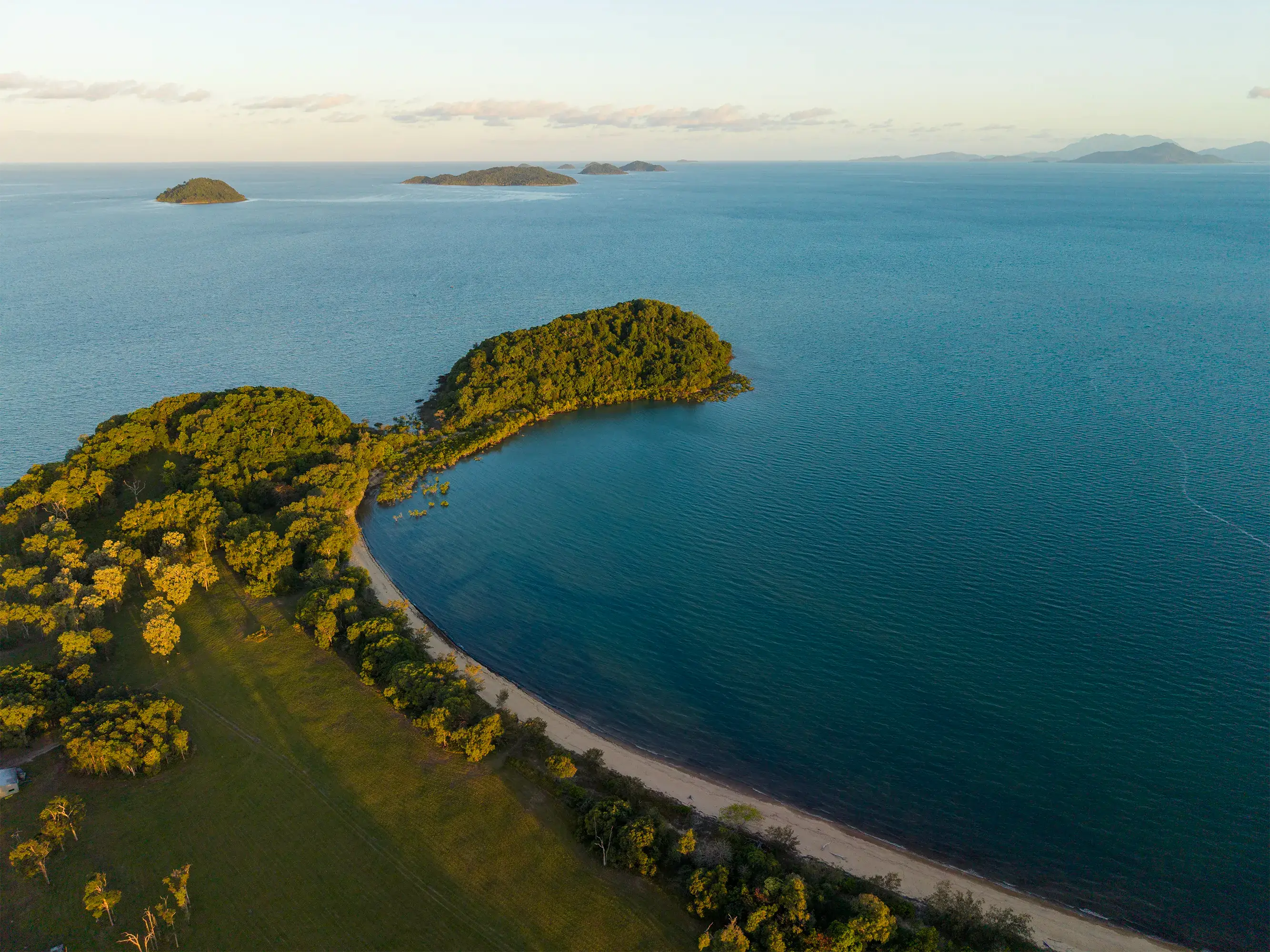 Late light along the headland and its beach, islands on the horizon